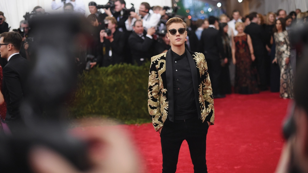 Justin Bieber trong trang phục Balmain tại sự kiện Met Gala năm 2015. Stylist Ugo Mozie đã cùng tạo nên chiếc áo khoác gấm thêu vàng cùng với nhà thiết kế Olivier Rousteing.